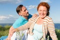 Happy Smiling Couple Relaxing on Green Grass and blue sky. Young Couple Lying on Grass Outdoor with water and sky background. Royalty Free Stock Photo