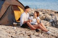 Happy smiling couple sitting face to face at rocky beach on near tent. Royalty Free Stock Photo