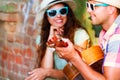 Happy smiling couple in sunglass and hat with guitar drinking j Royalty Free Stock Photo