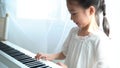 Satisfied Asian kid playing piano at home