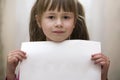 Happy smiling cute child girl holding white copy space sheet of drawing paper. Art education, creativity, advertisement concept Royalty Free Stock Photo