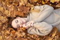 Happy Smiling Cute Girl With Closed Eyes Liying In The Autumn Leaves And Enjoying It, Holding Face And Smiling. Autumn Portrait In