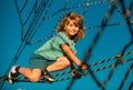 Happy smiling cute little child boy play monkey bars on the web in outdoor playground. Kids in rope park. Funny kids Royalty Free Stock Photo