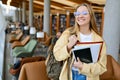 Happy girl student holding backpack standing in college library, portrait. Royalty Free Stock Photo