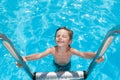 Happy smiling delightful little caucasian kid with eyes closed with pleasure in summer outdoor azure swimming pool during vacation