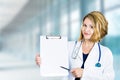 Happy smiling doctor with clipboard standing in hospital hallway Royalty Free Stock Photo