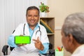 happy smiling doctor at hospital shownig green screen mobile phone to patient - concept of app promotion, advertisement Royalty Free Stock Photo