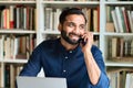 Happy indian business man working in office talking on phone making call. Royalty Free Stock Photo