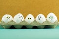 Happy smiling egg among angry eggs on paper tray. Positive attitude, optimistic thinking concept. Royalty Free Stock Photo