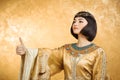 Happy smiling Egyptian woman like Cleopatra with thumbs up gesture, on golden background Royalty Free Stock Photo