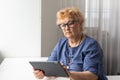 Happy smiling elderly woman with digital tablet computer having video call at home. Grandmother smiling enjoying social Royalty Free Stock Photo