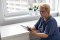 Happy smiling elderly woman with digital tablet computer having video call at home. Grandmother smiling enjoying social Royalty Free Stock Photo