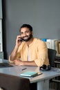 Smiling indian business man sitting at work desk talking on phone making call. Royalty Free Stock Photo