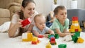 Happy smiling family with baby playing on carpet with toy blocks, bricks and cars. Concept of family having time Royalty Free Stock Photo