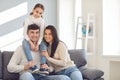 Happy smiling family. Daughter sits on fathers shoulders with mother sitting on the sofa Royalty Free Stock Photo