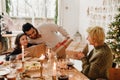 Happy family exchanging gifts while having dinner at table near Christmas tree Royalty Free Stock Photo