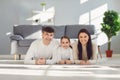 Happy smiling family hugging while lying on the floor in the room at home. C Royalty Free Stock Photo