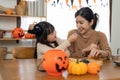 Happy smiling family mother and daughter making Halloween home decorations together while sitting at wooden table. Royalty Free Stock Photo