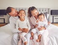 Happy, smiling and a family in pajamas on bed with small girls. Young mother and father with girl children in bedroom in Royalty Free Stock Photo