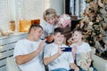 Happy smiling family sitting next to a beautifully decorated Christmas tree, greeting and showing gifts over the phone Royalty Free Stock Photo