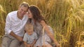 Happy smiling family sitting in wheat on the field Royalty Free Stock Photo