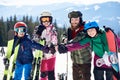 Happy smiling family on skis and snowboard in deep snow on background of winter mountains. Royalty Free Stock Photo