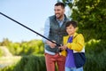 Happy smiling father and son fishing on river Royalty Free Stock Photo