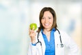 Happy smiling female doctor with green apple standing in hospital