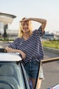 Happy excite female driver at car door at parking wait for friends to go on road trip in new vehicle Royalty Free Stock Photo