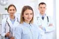 Happy smiling female patient with two cheerful doctors in the background. Medical and health care concept Royalty Free Stock Photo