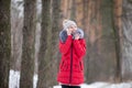 Happy smiling female in red winter jacket talks on mobile phone, outdoors in park Royalty Free Stock Photo