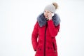 Happy smiling female in red winter jacket talks on mobile phone, outdoors, against the snow Royalty Free Stock Photo