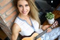 Happy smiling female sitting on table playing small ukulele Royalty Free Stock Photo