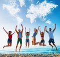 Happy smiling friends jumping over a blue sky with a world map made of clouds Royalty Free Stock Photo