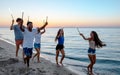 Happy smiling friends running at the beach with sparkling candles Royalty Free Stock Photo