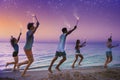 Happy smiling friends running at the beach with sparkling candles Royalty Free Stock Photo