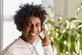 Happy gen z African American guy wearing headphones listening music at home. Royalty Free Stock Photo