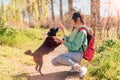 Happy smiling girl backpacker playing with black dog Royalty Free Stock Photo