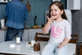 Happy smiling girl eating sandwich for breakfast and looking at the camera in the kitchen Royalty Free Stock Photo