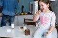 Happy smiling girl eating sandwich for breakfast and looking at the camera in the kitchen Royalty Free Stock Photo