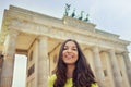 Happy smiling girl in front of Brandenburg Gate, Berlin, Germany. Beautiful young woman travel in Europe