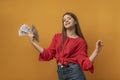 Happy smiling girl holding a fan of dollar bills in hand on a yellow background. Young business woman Royalty Free Stock Photo