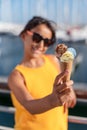 Happy, smiling girl holding ice cream cone with colorful ice cream balls. Sunny sea coastline at the background Royalty Free Stock Photo