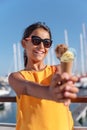 Happy, smiling girl holding ice cream cone with colorful ice cream balls. Sunny sea coastline at the background Royalty Free Stock Photo