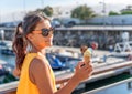 Happy, smiling girl holding ice cream cone with colorful ice cream balls. Sunny sea coastline at the background Royalty Free Stock Photo