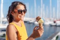 Happy, smiling girl holding ice cream cone with colorful ice cream balls. Sunny sea coastline at the background Royalty Free Stock Photo
