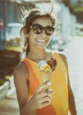 Happy, smiling girl holding ice cream cone with colorful ice cream balls. Sunny sea coastline at the background Royalty Free Stock Photo