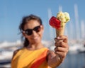 Happy, smiling girl holding ice cream cone with colorful ice cream balls. Sunny sea coastline at the background Royalty Free Stock Photo