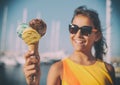 Happy, smiling girl holding ice cream cone with colorful ice cream balls. Sunny sea coastline at the background Royalty Free Stock Photo