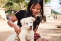 Happy smiling girl holding a white dog puppy in her hand outdoor